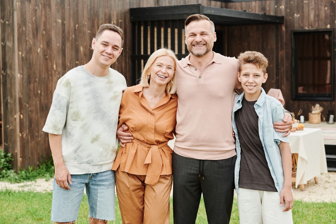 Smiling family of four posing outdoors, capturing love and togetherness.