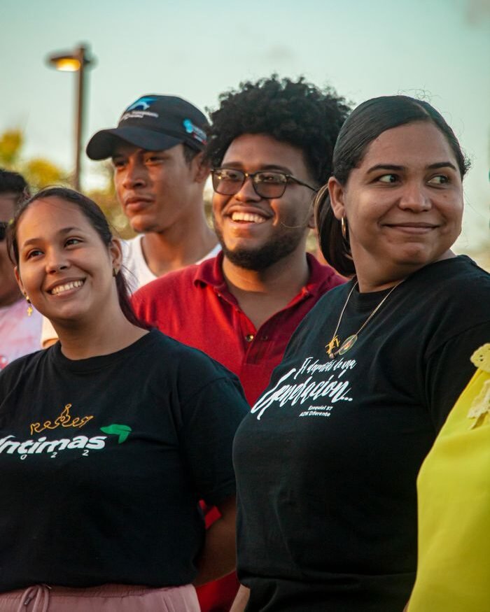 A diverse group of young adults smiling outdoors during a sunny day, fostering friendship and happiness.